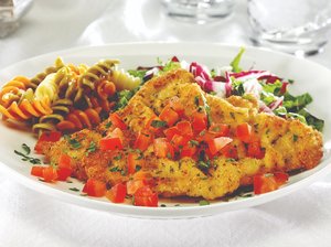 Easy Veal milanese with chopped tomato garnish, side salad, and pasta.