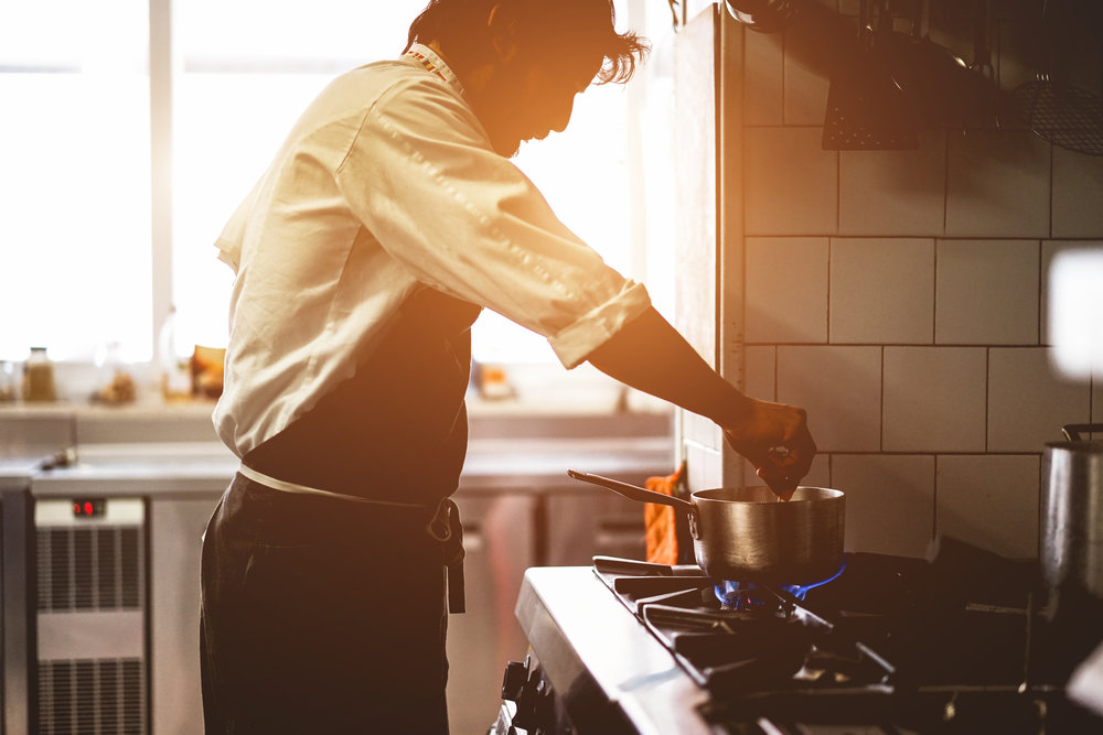 Male chef cooking in restaurant kitchen preparing - Silhouette cook at work during dinner service - Italian style cuisine, lifestyle and healthy food concept - Focus on face