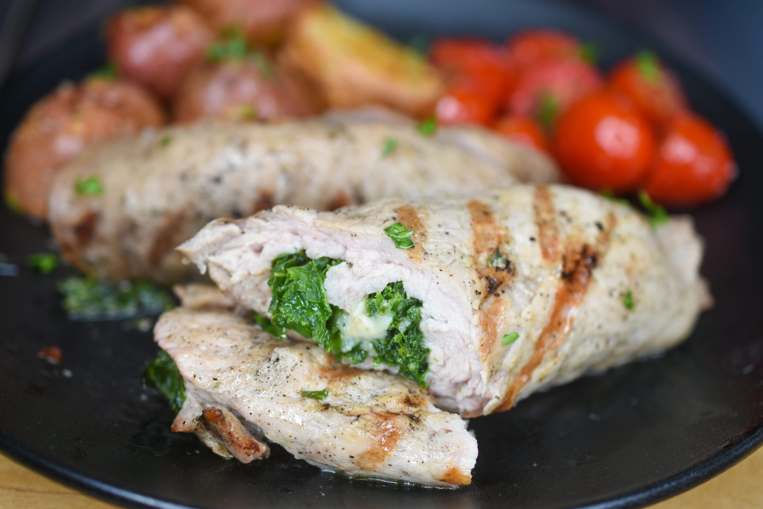 Veal Cutlets are stuffed with cheese and spinach and grilled to perfection leaving grilled marks and a delicious flavor, served with tomatoes, and red tomatoes.