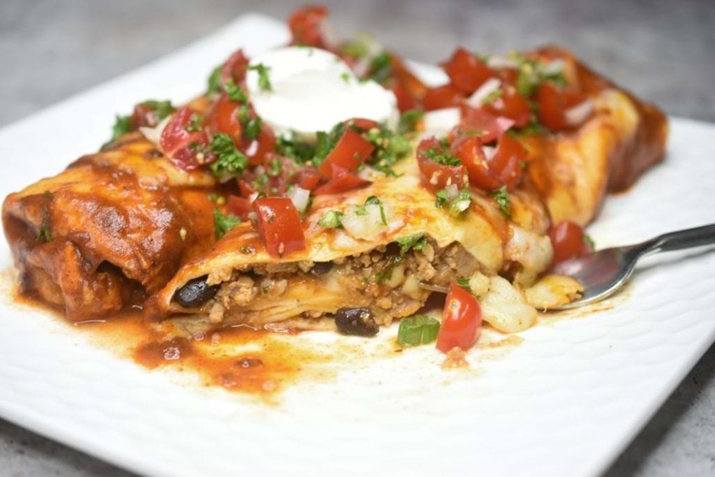 A twist on enchiladas, these Ground veal enchiladas are served with a red enchiladas sauce, packed with cheese meat, and beans, and served with tomatoes and sour cream on top.