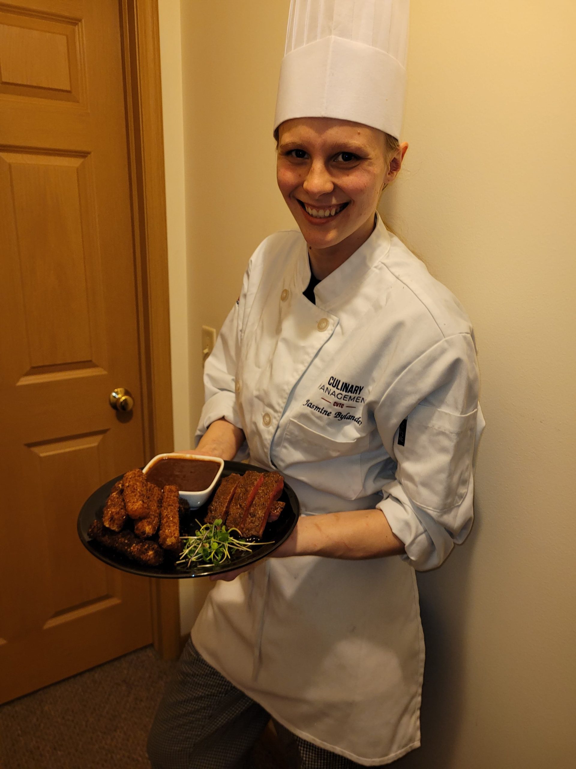 Jasmine Bylander stands in her chef coat with her competition entry, as the one of the peoples choice winners of the 2022 National Collegiate Veal Competition.