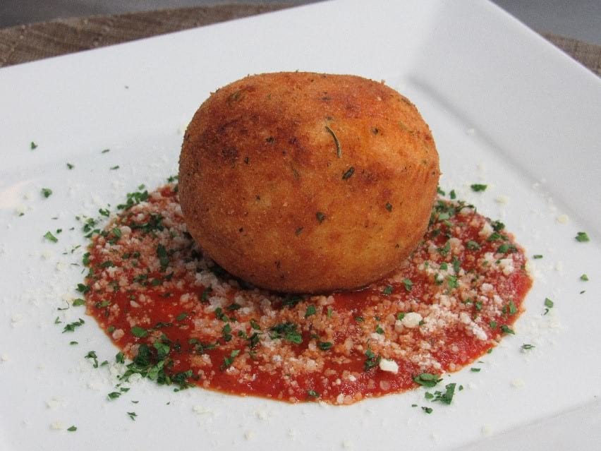 Potato Bolognese croquettes served over some mozzarella and garnished with fresh basil ad parmesan cheese