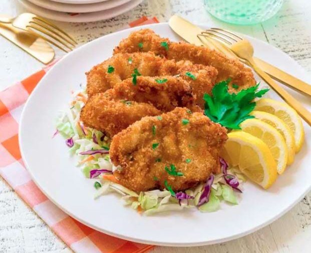 Wiener Schnitzel, crispy golden fried veal cutlets on a bed of cole slaw and set with wedges of lemon.