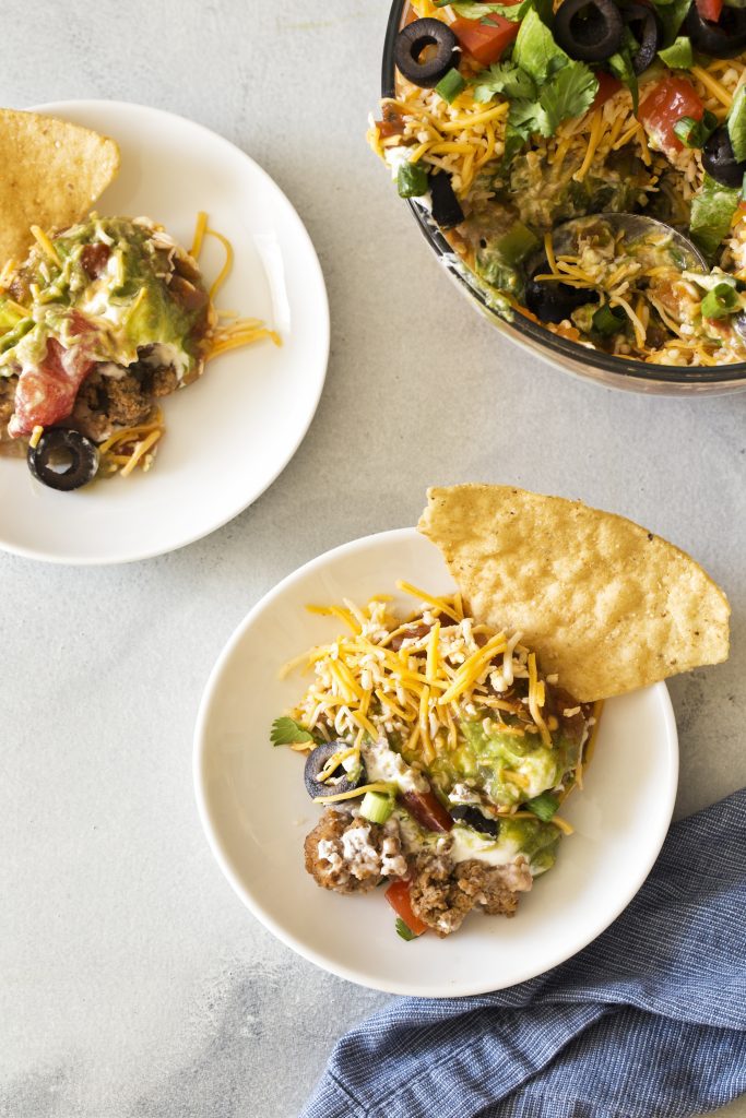7-layer taco dip on a plate with a chip in it